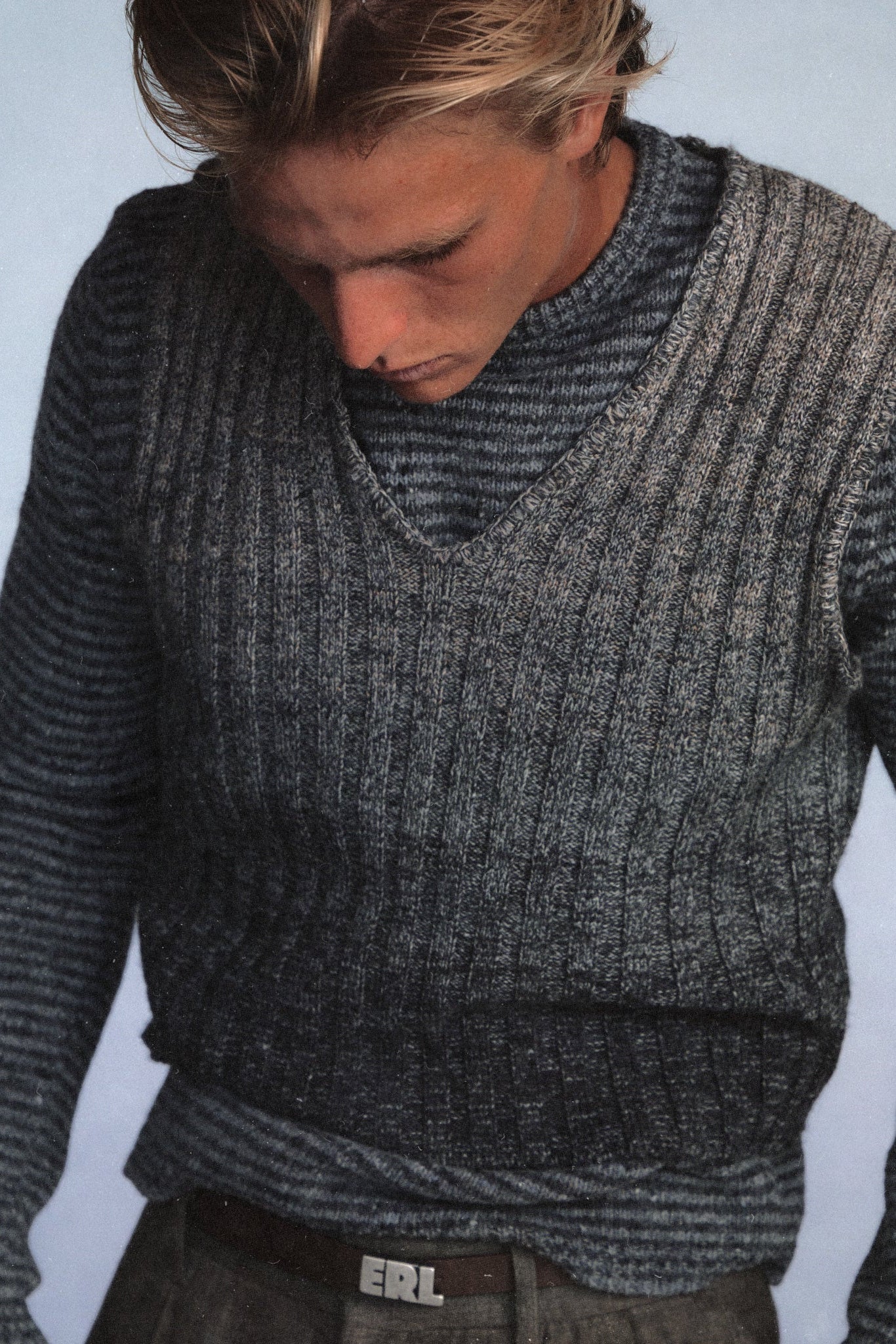 Man wearing a gray knitted sweater against a light blue background