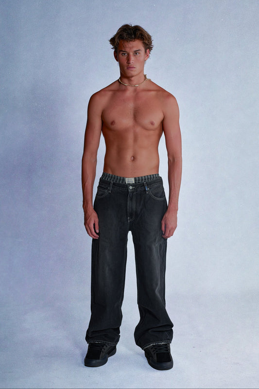 Man wearing black jeans on a plain background