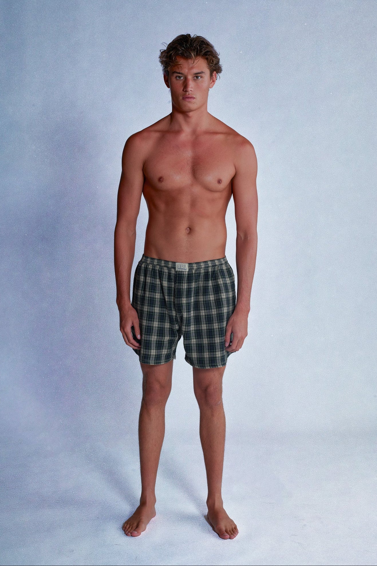 Man wearing plaid shorts against a plain background